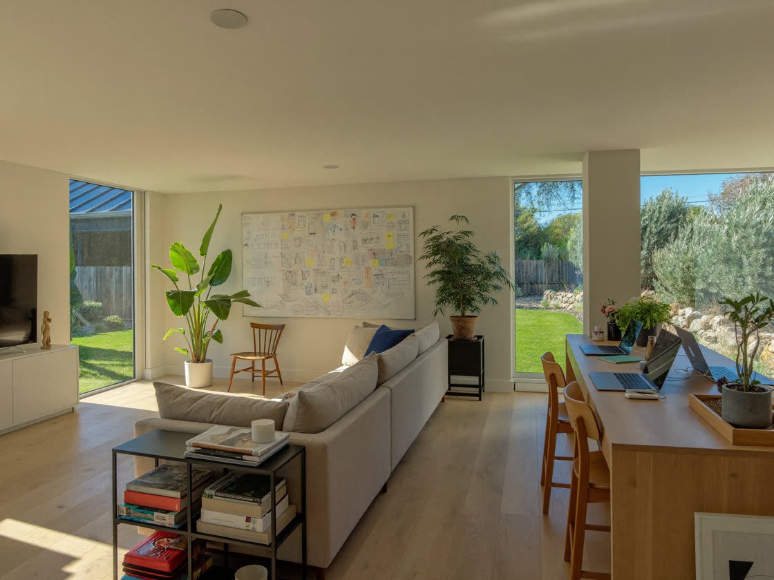 Sunny open-plan living and work space in a medium single-family house with a whiteboard wall and backyard view